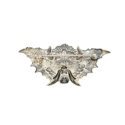 Quirky winged devil face brooch in sterling silver and orange enamel