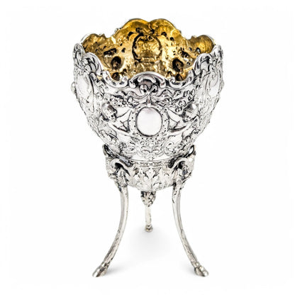 Hanau sterling silver tripod cup with repoussé putti, floral garlands, and ram’s head feet, Baroque Revival, c. 1880s