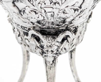 Hanau sterling silver tripod cup with repoussé putti, floral garlands, and ram’s head feet, Baroque Revival, c. 1880s