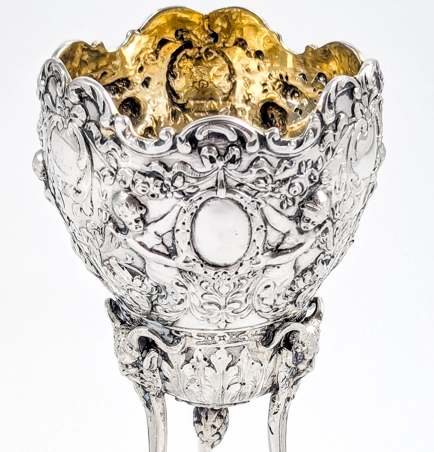 Hanau sterling silver tripod cup with repoussé putti, floral garlands, and ram’s head feet, Baroque Revival, c. 1880s