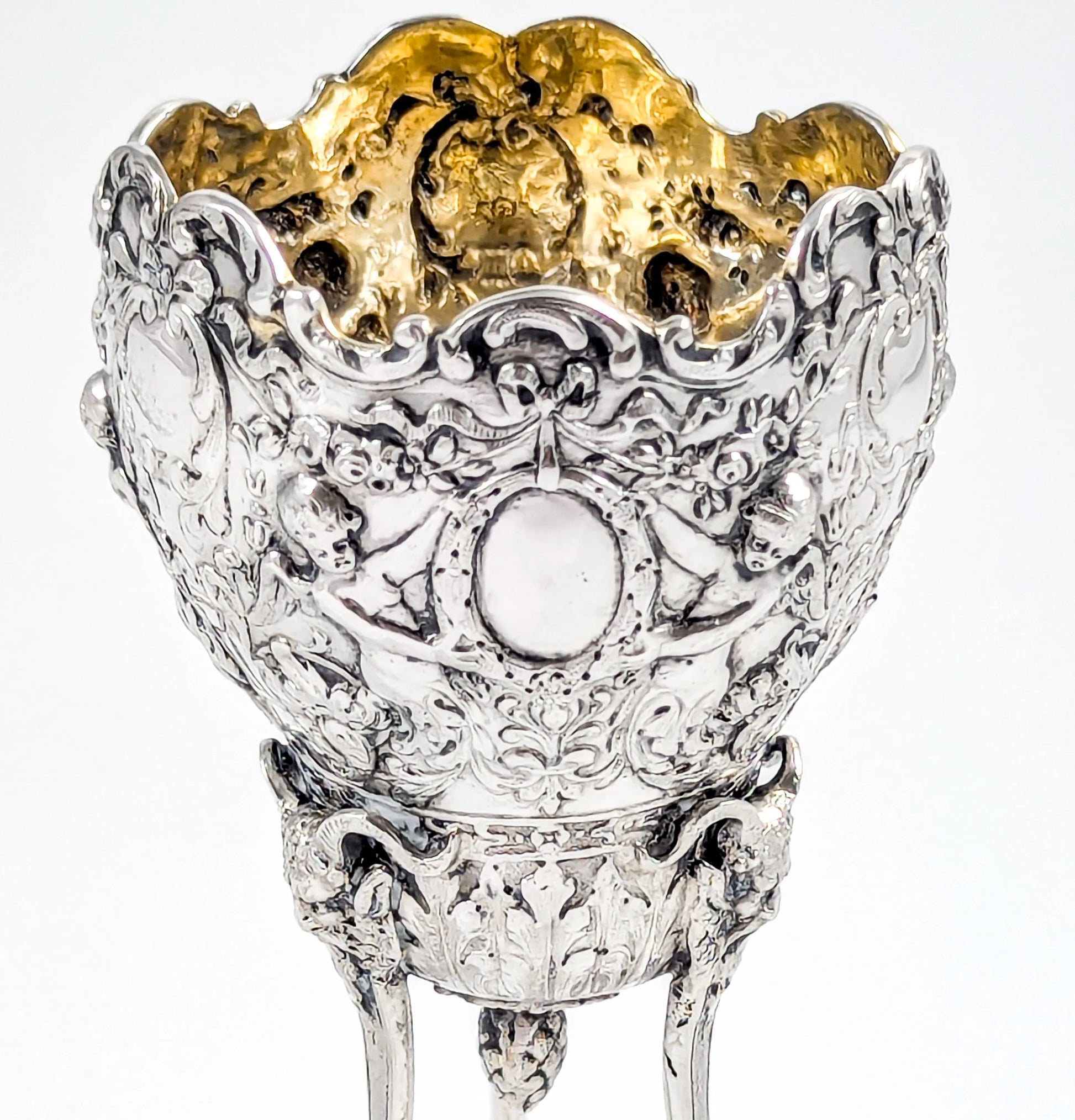 Hanau sterling silver tripod cup with repoussé putti, floral garlands, and ram’s head feet, Baroque Revival, c. 1880s