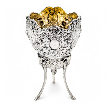 Hanau sterling silver tripod cup with repoussé putti, floral garlands, and ram’s head feet, Baroque Revival, c. 1880s