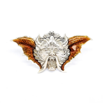 Quirky winged devil face brooch in sterling silver and orange enamel