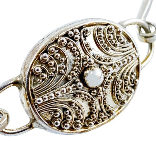 Suarti Bali sterling silver bangle bracelet with an oval medallion decorated with beaded scrolls